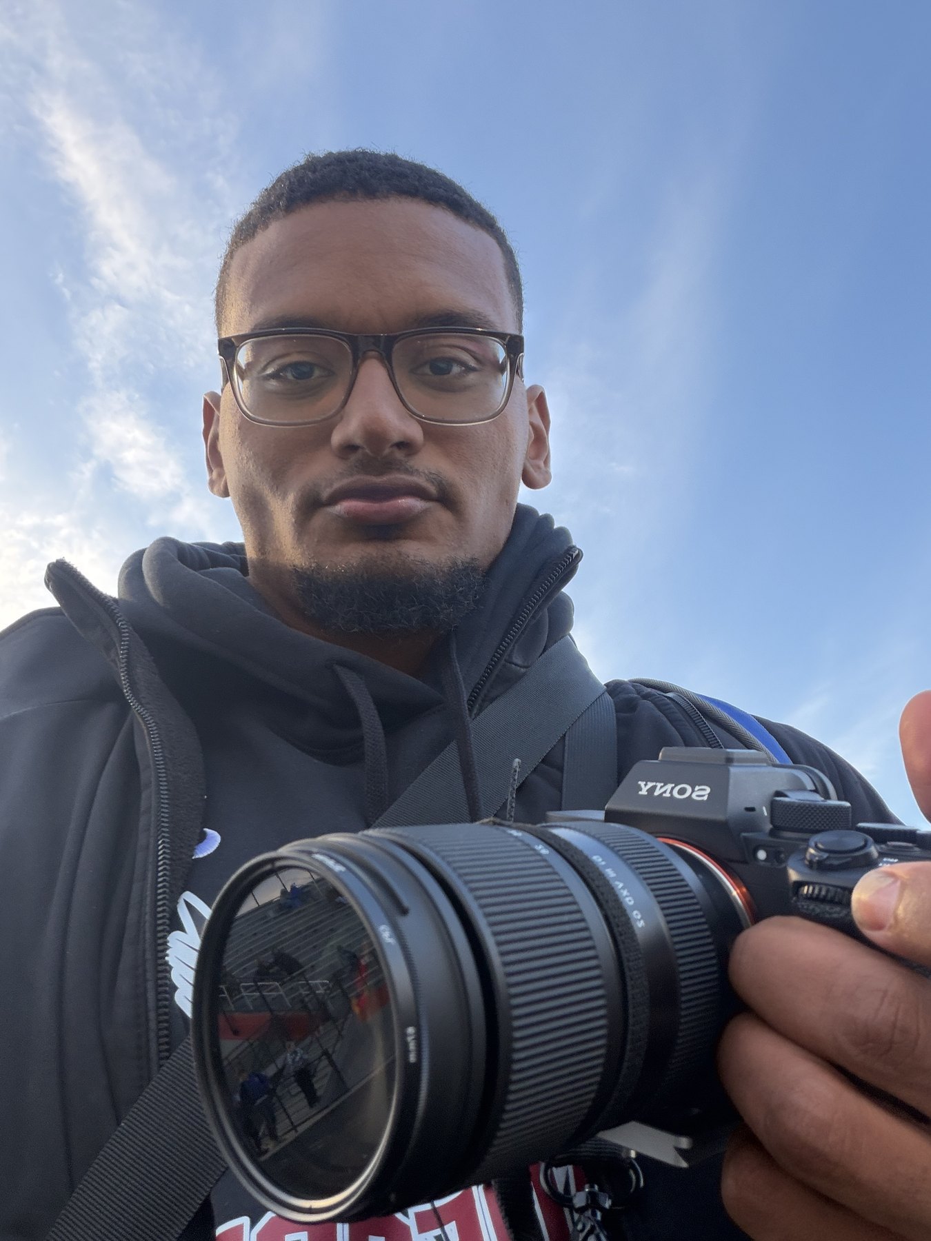 Ed holding a camera outdoors.
