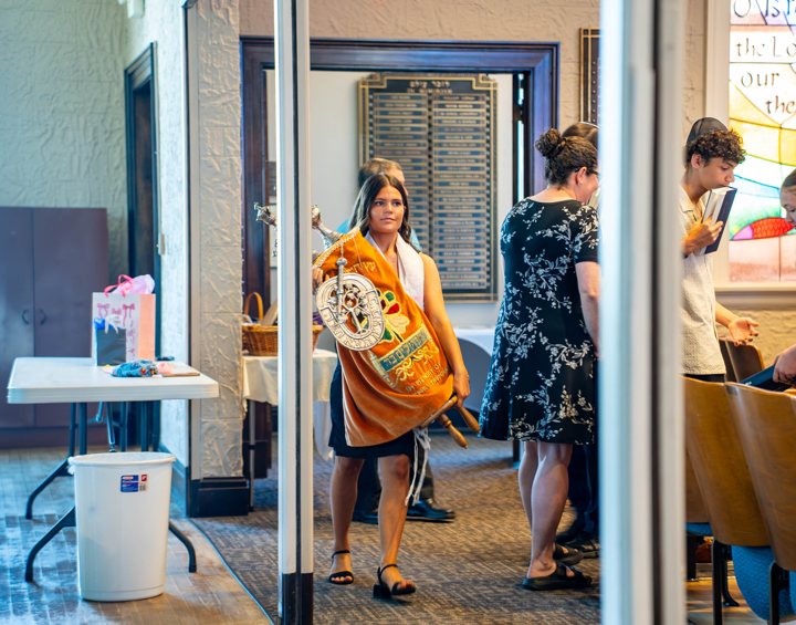 A participant carries a covered Torah through a doorway.