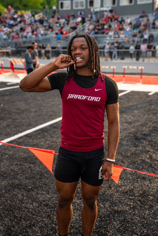 An athlete poses with a medal at a track meet.