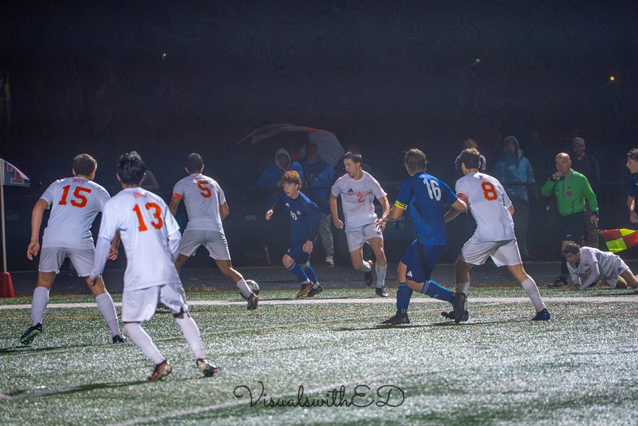 Wide view of both teams competing for the ball under the stadium lights.