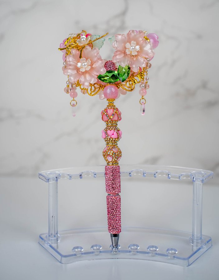 A decorative pink floral pen displayed on a clear stand.