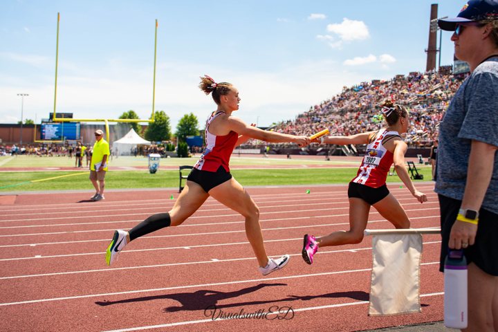 Two runners exchange a baton during a relay race.
